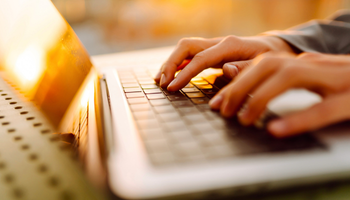 A woman is typing on her laptop computer.